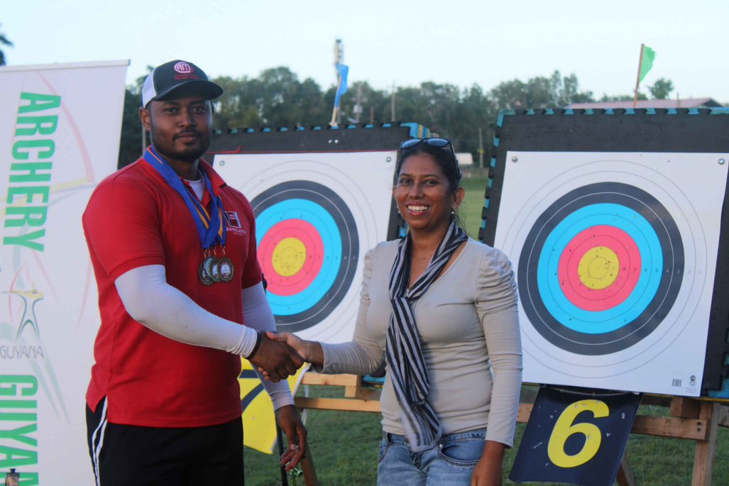 President of Archery Guyana, Ms. Vidushi Persaud-McKinnon on right congratulating Mr. Jeewanram Persaud for securing Gold in Men Recurve