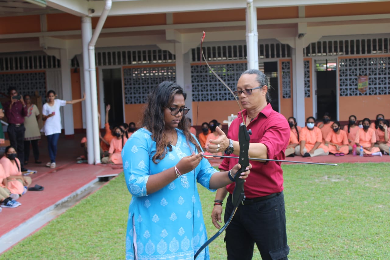 Nicholas Hing of Archery Guyana guides female archer of SVN School