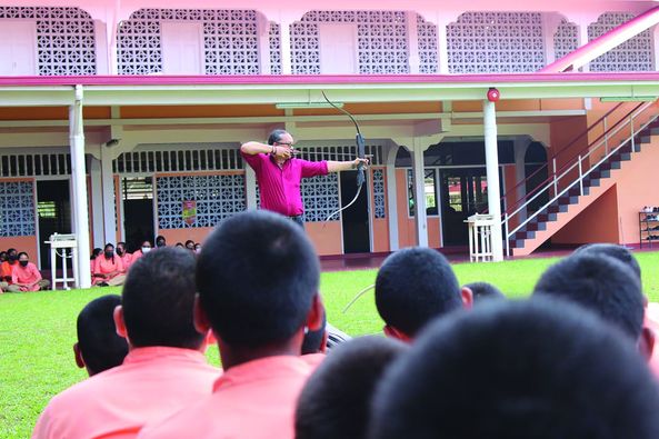 Nicholas Hing demonstrates techniques in archery to students of SVN school